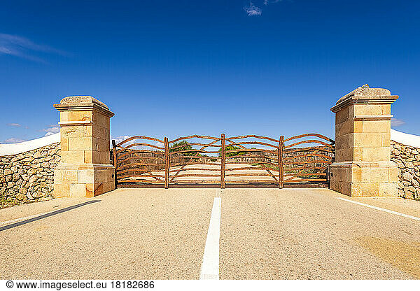 Spain  Balearic Islands  Menorca  Wooden gate in middle of asphalt road
