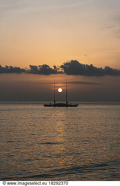 Spain  Balearic Islands  Sun setting over sailboat floating at sea