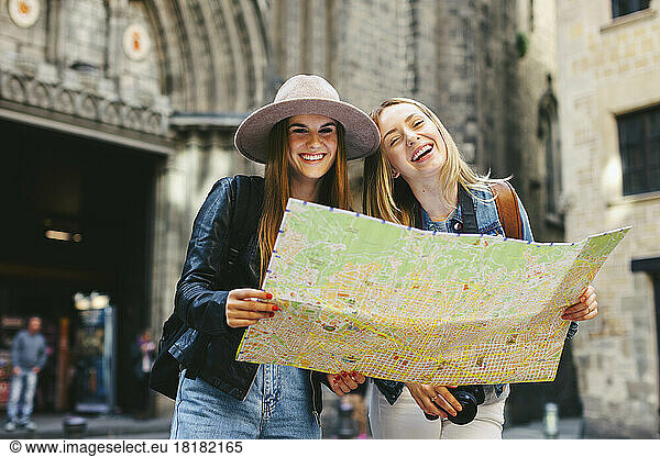 Spain  Barcelona  two happy young women reading map