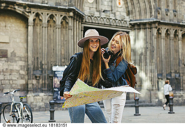 Spain  Barcelona  two happy young women with camera and map