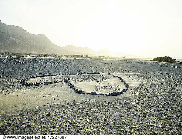 Spain  Canary Islands  Fuerteventura  Heart shape made of stones on sandy beach Playa de Cofete at sunset