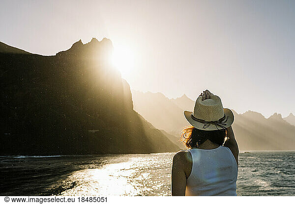 Spain  Canary Islands  Young woman admiring sunset over coastal mountains of Macizo de Anaga range
