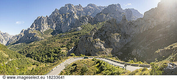 Spain  Castile and Leon  Posada de Valdeon  Panoramic view of Picos de Europa range in summer with asphalt road in foreground