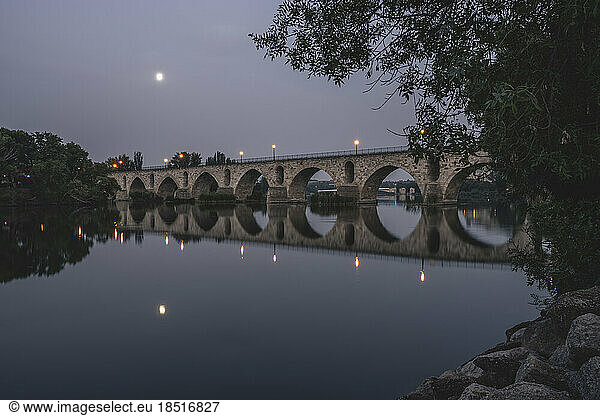 Spain  Castilla y Leon  Zamora  Puente de Piedra bridge reflecting in Douro river at dusk