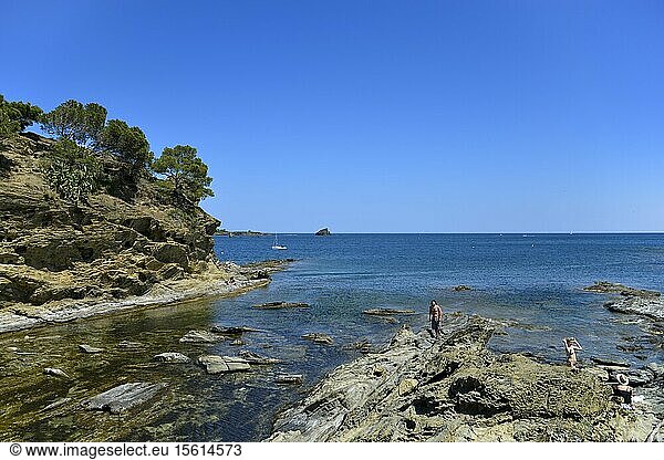 Spain Catalonia Costa Brava province of Girona Cadaques Cap de Creus vacationers walking on rocks with the sea in the background