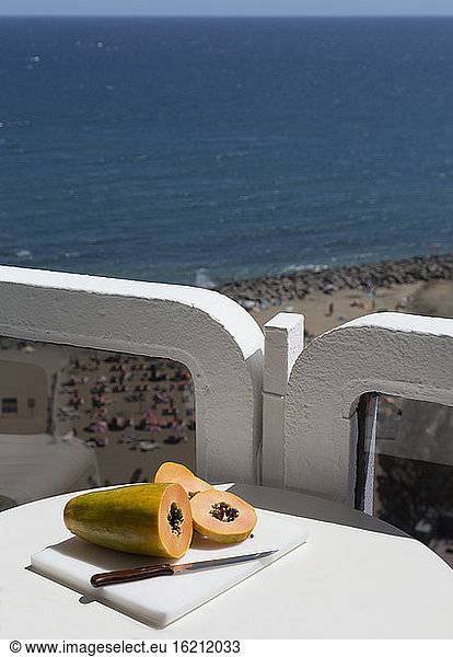 Spain  Gran Canaria  Papaya with knife on table near beach