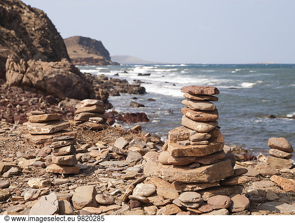 Spanien  Balearen  Menorca  Steinhaufen an der Küste von Menorca  Gebiet mit rotem Boden