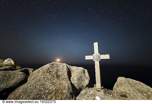 Spanien  Galicien  Ferrol  Monduntergang in einem Ort an der galicischen Küste mit einem Steinkreuz im Vordergrund