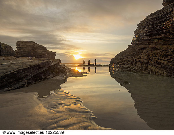 Spanien Galizien Ribadeo Playa de Aguas Santas bei Sonnenuntergang kleine Personen am Strand