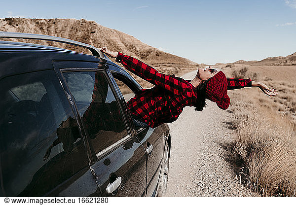 Spanien  Navarra  Weibliche Touristin lehnt sich aus dem Autofenster über den Feldweg in Bardenas Reales