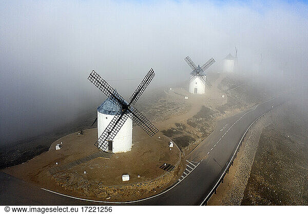 Spanien  Provinz Toledo  Consuegra  Luftaufnahme einer Landstraße  die an historischen Windmühlen vorbeiführt  bei nebligem Wetter