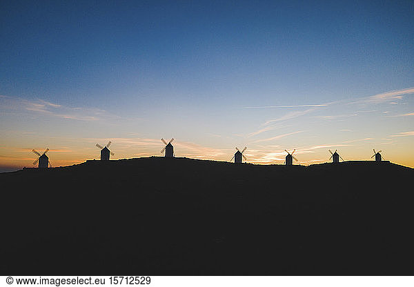 Spanien  Provinz Toledo  Consuegra  Silhouetten von Windmühlen  die im Morgengrauen auf einem Hügel stehen