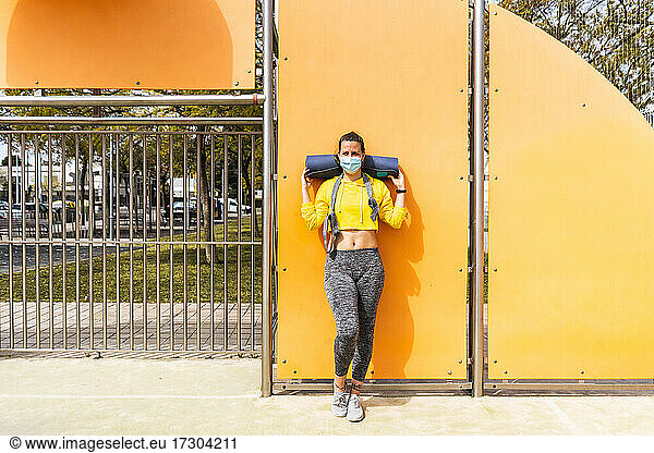 Spanische Frau mit Sportkleidung  Matte und Schutzmaske im Sportbereich