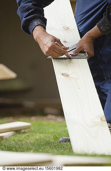 Spanischer Zimmermann mit Winkel zur Markierung des Schnitts auf dem Brett für die Konstruktion