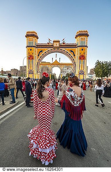 Spanish women with flamenco dresses in front of the illuminated Portada  entrance gate  Feria de Abril  Sevilla  Andalusia  Spain  Europe