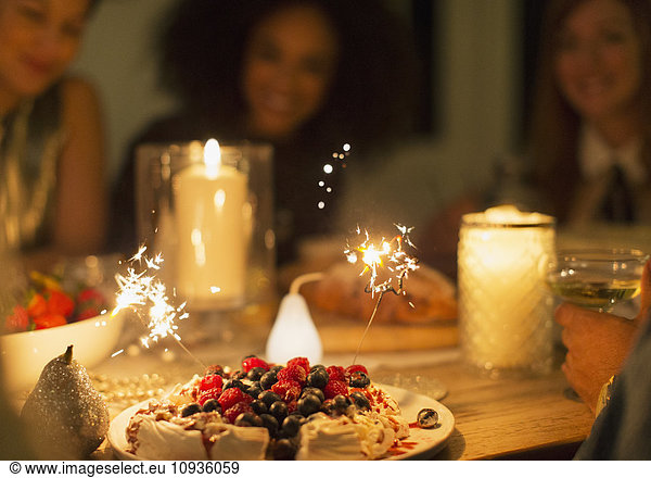 Sparklers on berry pavlova dessert on candlelight table