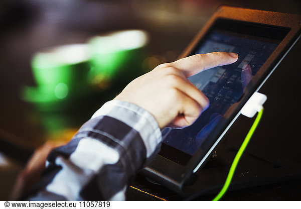 Specialist coffee shop. A person using a touch screen at a till.