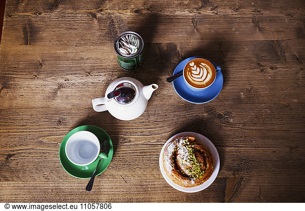 Specialist coffee shop. view of a table top with a cup of coffee  a teapot and tea cup  and a pastry on a plate.