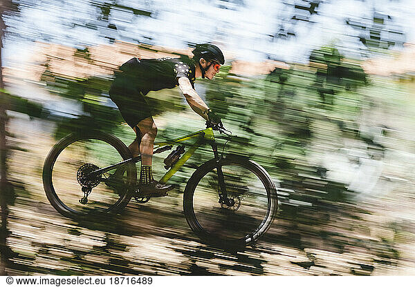Speed blur of male mountain bike cyclist going downhill