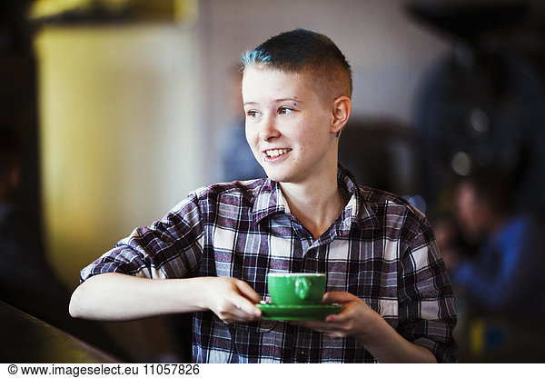 Spezialisiertes Kaffeehaus. Eine junge Person  die eine Tasse Kaffee trägt.