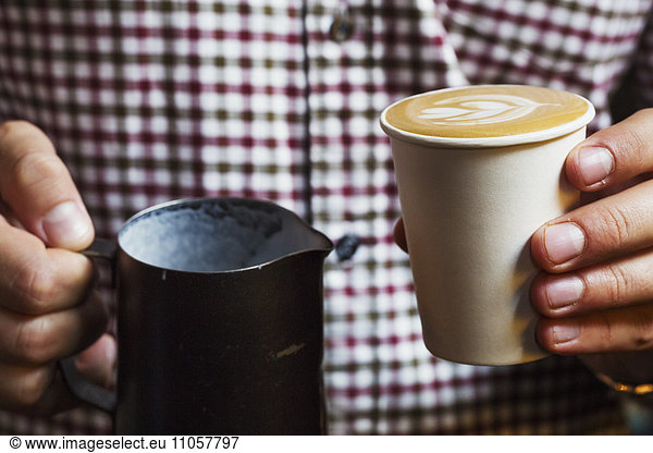 Spezialisiertes Kaffeehaus. Eine Person  die eine frische Tasse Kaffee hält.