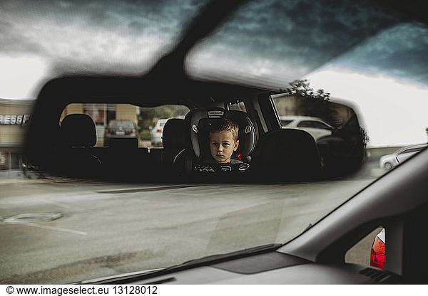 Spiegelung eines Jungen im Rückspiegel eines Autos