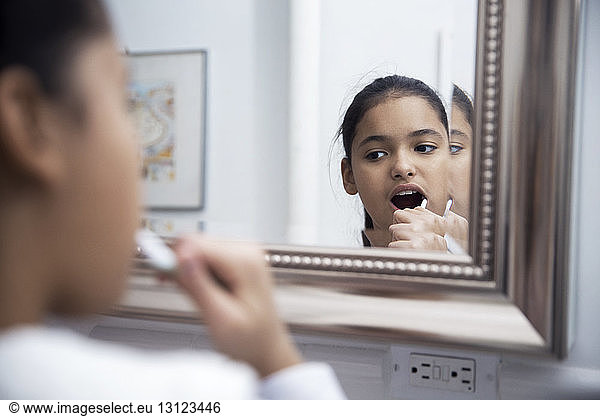 Spiegelung eines Mädchens beim Zähneputzen
