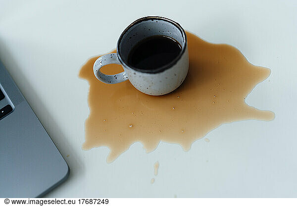 Spilled coffee by laptop on desk
