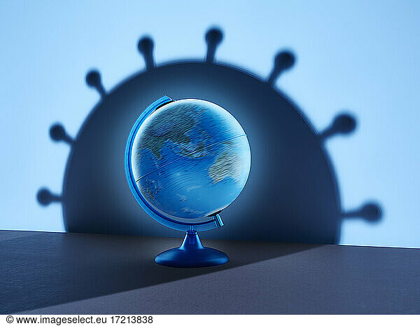 Spinning globe casting large blue coronavirus bacterium shadow