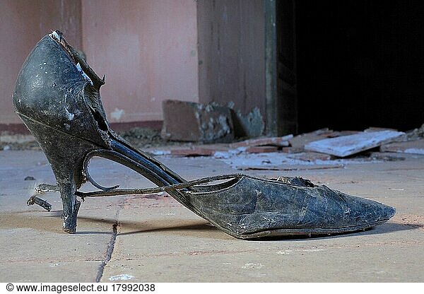 Spitzer Damenschuh mit Riemen  schwarzer Tanzschuh mit Riemchen am Boden  Verrotteter Schuh am Boden  Schuhwrack  vergammelter Treter  ausgelatschter Schuh  abgetragener Schuh