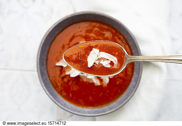 Spoon of vegan tomato soup with coconut flakes