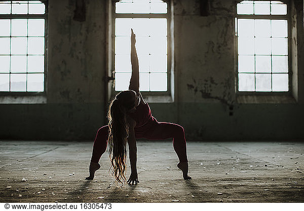 Sportler übt Yoga-Position in verlassener Fabrik