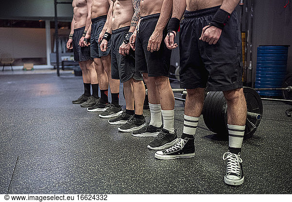 Sportler ohne Hemd mit Sportschuh und Shorts im Fitnessstudio