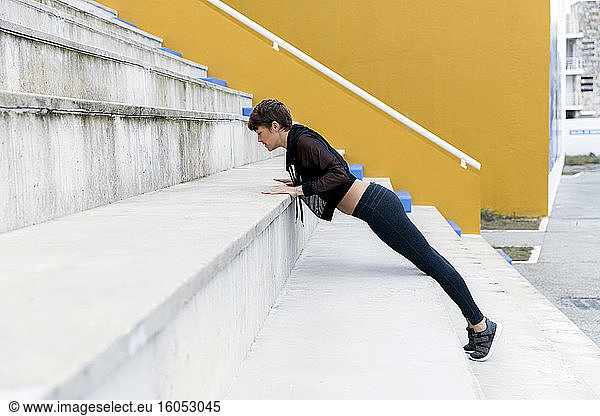 Sportliche Frau beim Plankentraining auf der Treppe