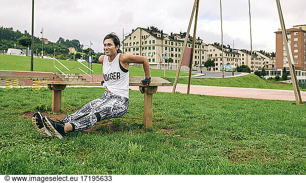 Sportliche Frau beim Training auf einer Parkbank
