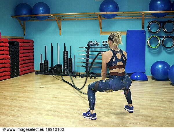 Sportliche junge Erwachsene  die sich auf ein Fitnesstraining mit Seilen im Fitnessstudio konzentriert