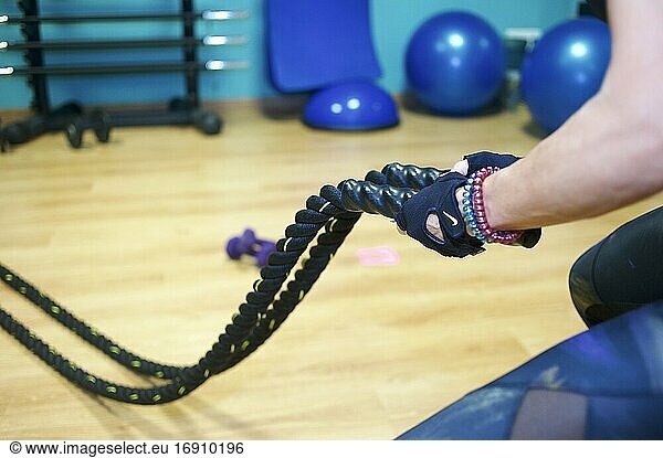 Sportliche junge Erwachsene  die sich auf ein Fitnesstraining mit Seilen im Fitnessstudio konzentriert