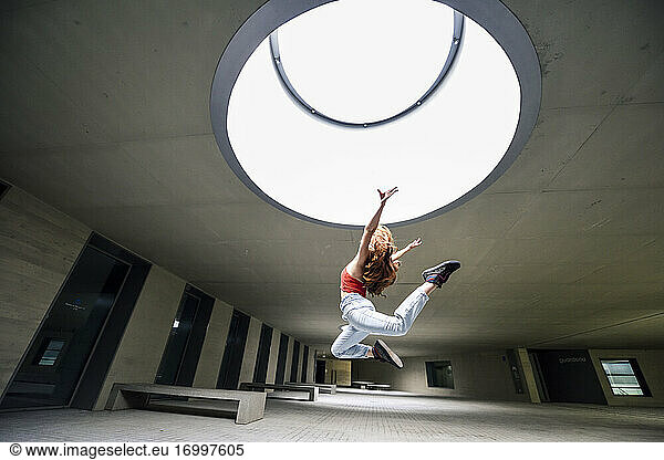 Sportliche junge Frau springt im Innenhof