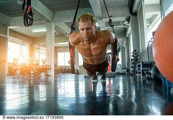 Sportsman exercising with battle ropes during strength workout i