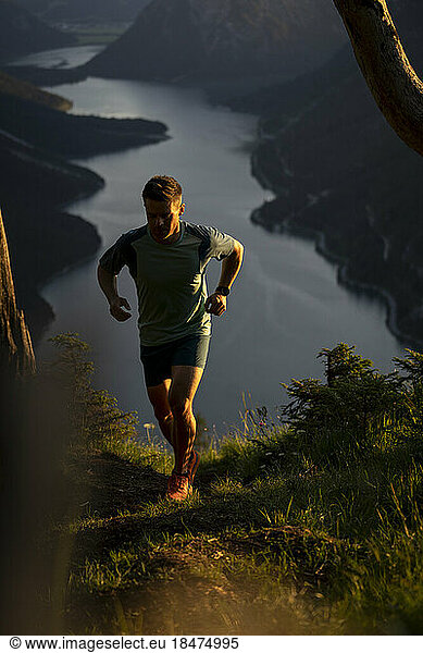 Sportsman jogging on mountain at sunset