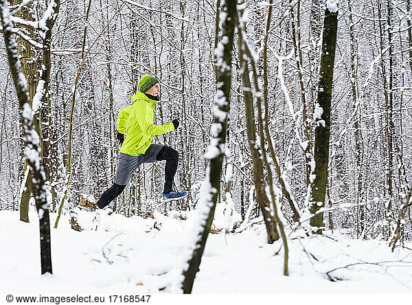 Sportsman running on snow in forest during winter