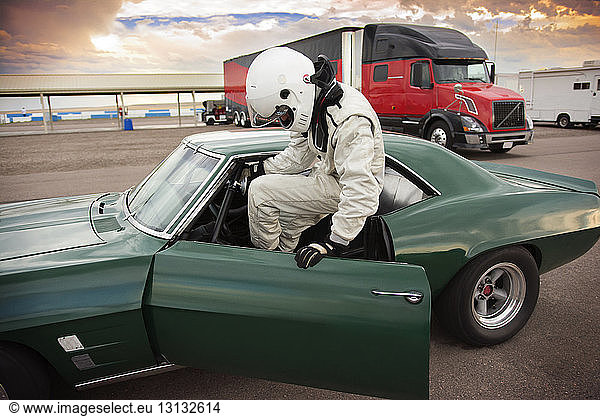 Sportsman sitting in vintage car while preparing for sports race