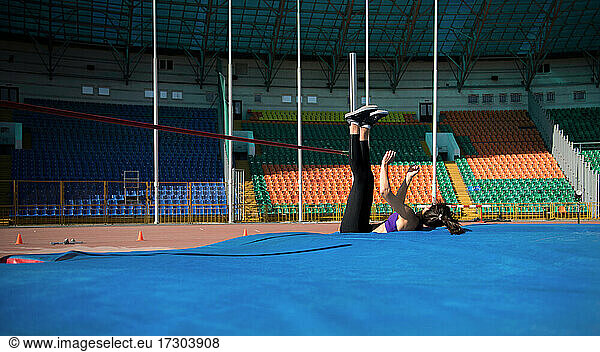 Sportswoman falling on mat after high jump