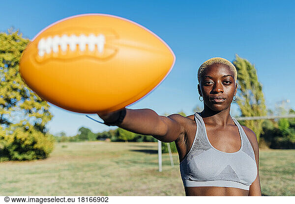 Sportswoman showing ball on sunny day