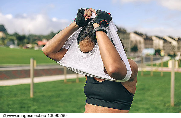 Sportswoman taking off t-shirt at park