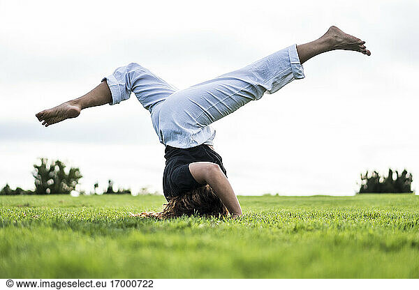 Sportswoman turning cartwheel on grass in park sky