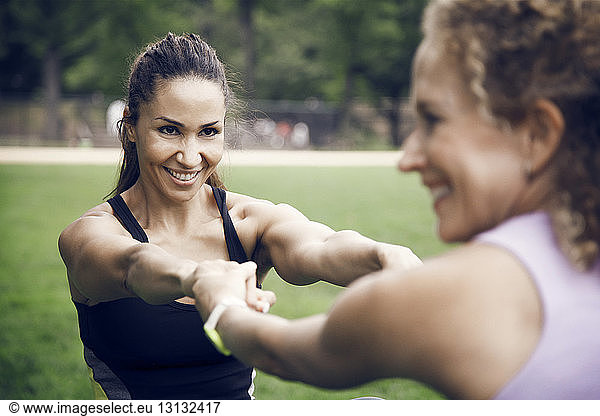 Sportswomen holding hands while stretching at park