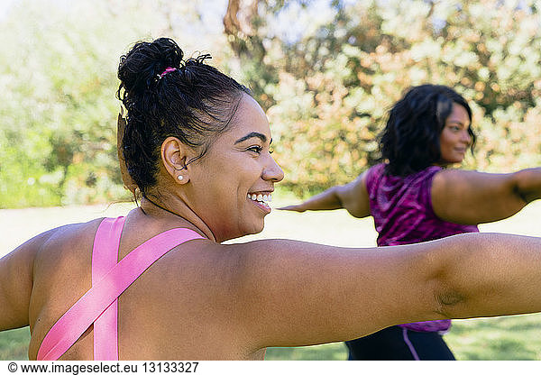 Sportswomen with arms outstretched exercising at park