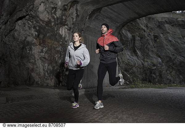 Sporty couple jogging in tunnel