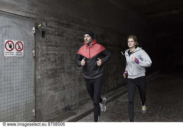 Sporty couple running in tunnel